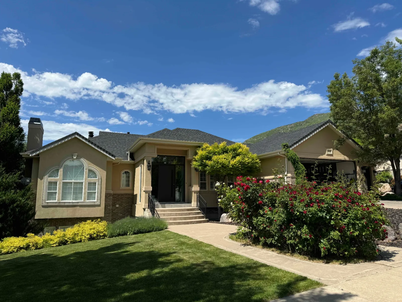 Stucco home with brick accents and manicured landscaping against the Wasatch foothills